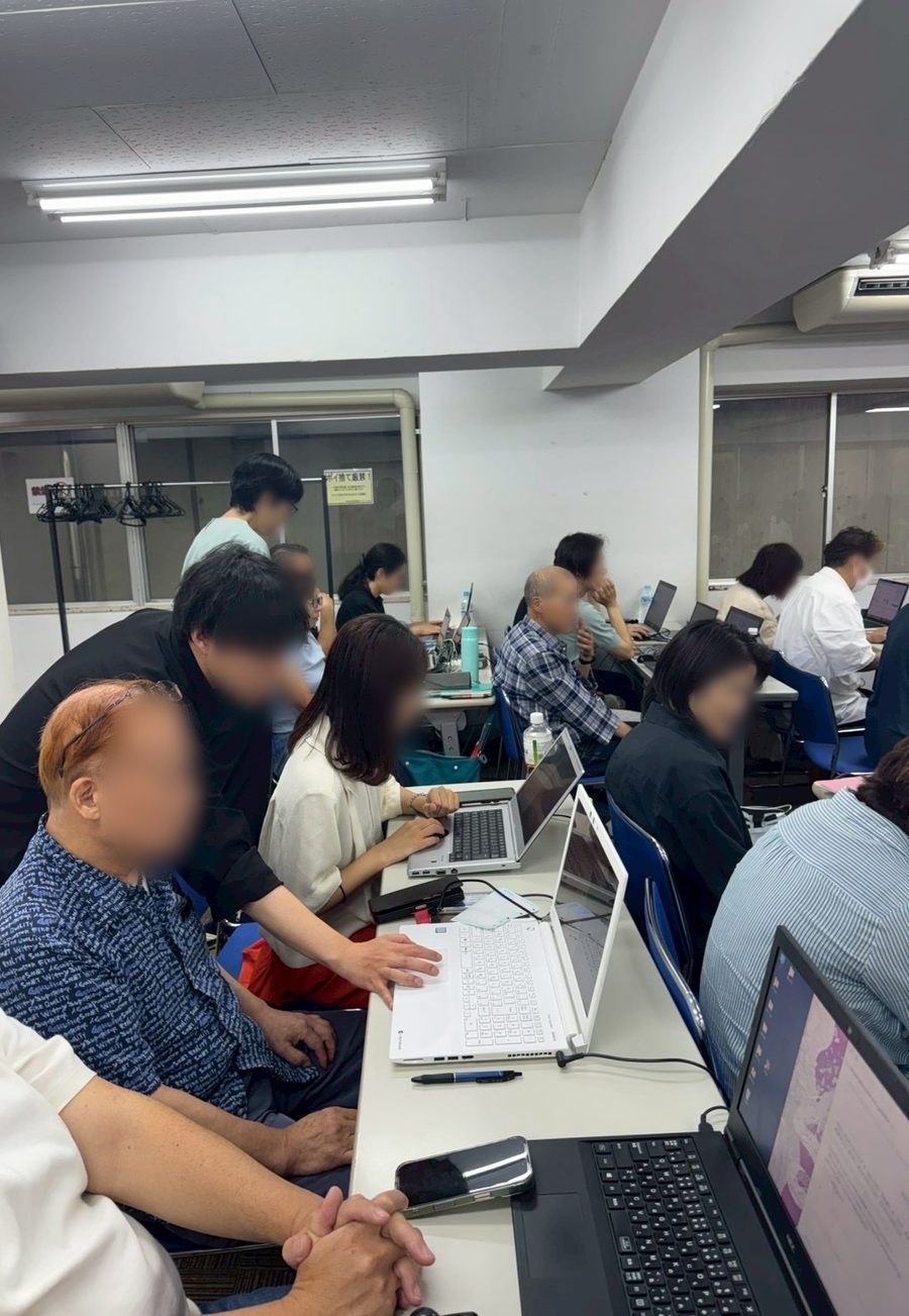 講師が受講者の横につき、画面を見ながら教えている様子